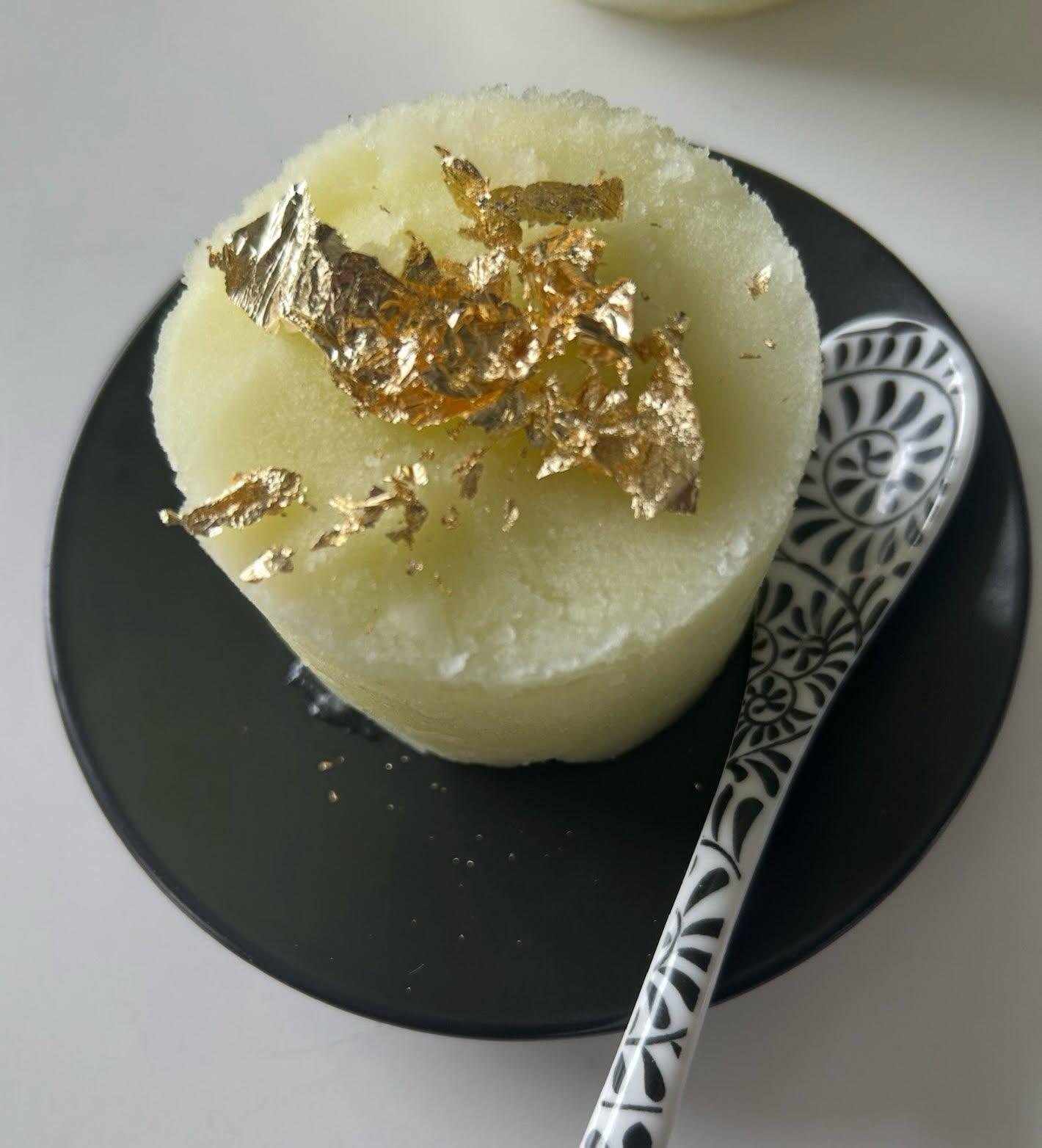 Apple Riesling Sorbet topped with gold leaf on a black plate